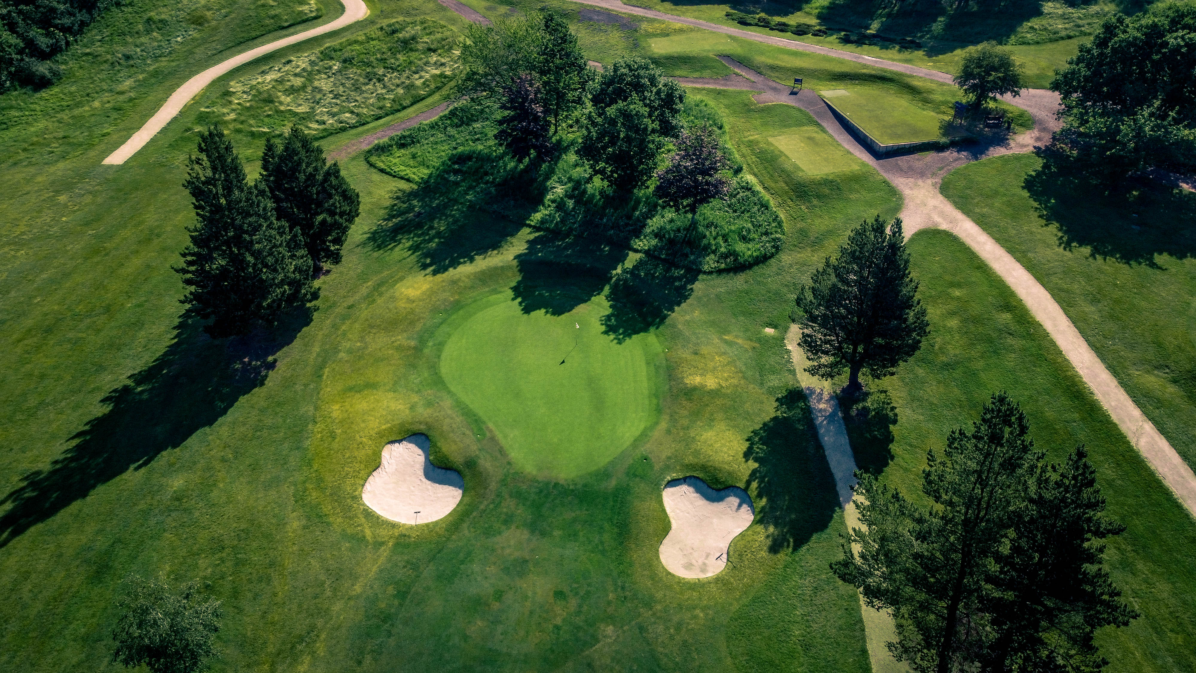 Drone footage of a golf course showing a green surrounded by bunkers.